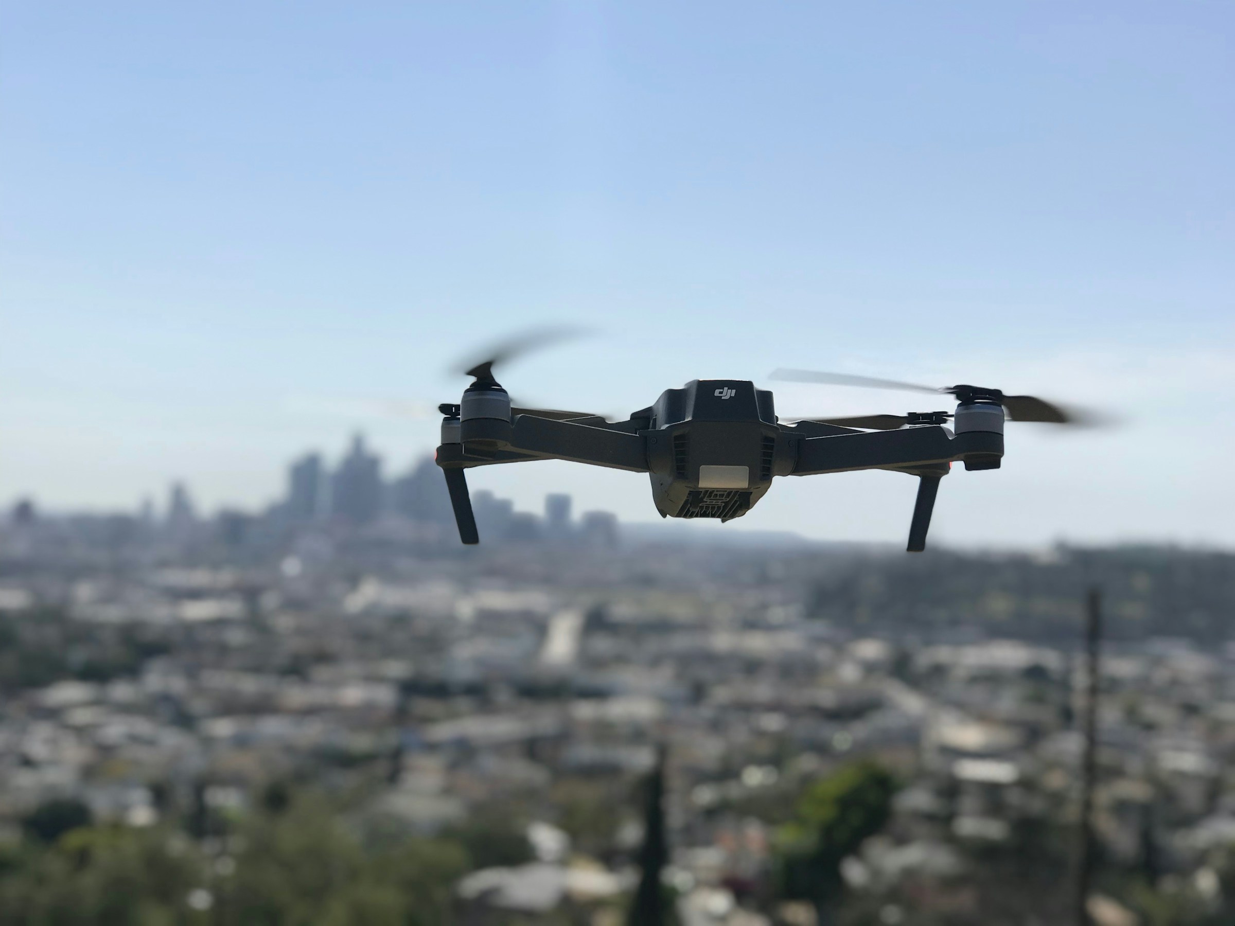A delivery drone hovers above a city skyline.